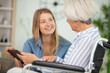 © auremar - cheerful woman taking care of her grandmother in wheelchair