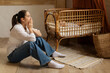 © Home-stock - Young woman sitting tired and depressed by the crib while baby sleeping. Postpartum depression concept