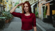 © Krakenimages.com - Woman saluting on a lively city street with vibrant buildings and plants, showcasing fashion in a casual yet stylish red top, surrounded by urban scenery and natural elements.