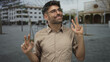 © Krakenimages.com - Friendly smiling young man wearing glasses and a beige shirt showing peace sign with both hands on street; joy.