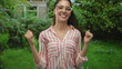 © Krakenimages.com - Woman wearing striped shirt and glasses smiling and raising arms in green forest; celebration joy.