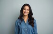 © Oleksandr - Young brunette woman with dark wavy hair smiles happily. She wears a blue denim shirt against a plain grey background. Her facial expression is friendly and positive.