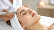 © photostockatinat - A beautiful woman receiving a professional facial treatment at a spa. The woman appears relaxed and content as the technician applies the treatment.