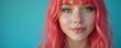 © Lubov - Young woman with vibrant pink hair and striking colorful eye makeup smiles. Her blue eyes sparkle against a solid blue backdrop, radiating a sense of fun and youthful energy.