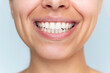 © Марина Демешко - Close-up of a healthy, white smile of a young woman on a light grey background. Dental care, oral hygiene and natural beauty concept with clean, well-aligned teeth and smooth lips