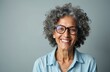 © Lubov - Smiling mature Indian woman with curly grey hair, glasses. Wears blue collared shirt, looking directly at camera with cheerful, pleasant expression. Head, shoulders visible in close-up portrait.