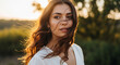 © Misbah - A beautiful young woman with long brown hair is standing in a field at sunset, looking off into the distance with a thoughtful expression
