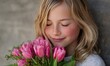 © simba kim - A young girl with blonde hair, highlighted with delicate glitter, is captured in a moment of pure bliss as she brings a vibrant bouquet of pink tulips to her face