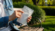 © Hadi - Hand Holding White Pouch Sitting on Bench Outdoors