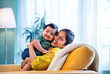 © StockImageFactory - Indian mom and infant son cuddling on sofa, smiling warmly in bright, modern home