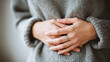 © kora studio - woman in cozy sweater gently holds her hands on her belly, conveying sense of warmth and comfort. soft texture of sweater adds to