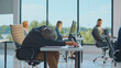 © Videophilia - Stressed senior businessman sleeping at a desk in a modern office, experiencing exhaustion and burnout while colleagues work around him, representing corporate overload and stress