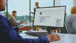 © Videophilia - Business professional analyzes financial reports and builds charts in a spreadsheet on a desktop computer in a modern office with colleagues working in the background