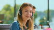 © Videophilia - Young woman customer service representative smiling and looking at the camera, wearing a headset for providing online or phone support in a modern call center office