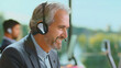 © Videophilia - Mature customer service agent with gray beard and headset smiling confidently while speaking with a client in a modern office, providing friendly, professional support and assistance