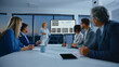 © Videophilia - Business executive presenting global market data and financial charts on a large screen to a diverse team of professionals in a modern corporate conference room during an evening meeting
