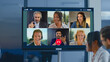 © Videophilia - Diverse business professionals conducting a virtual meeting on a large screen, engaging in a video conference from various locations, symbolizing global connection and remote teamwork