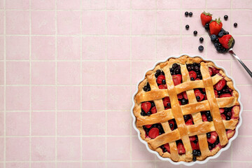 Wall Mural - Baking dish with tasty berry pie and spatula on pink tile background