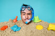 © Elizaveta - Man buried in sand with snorkel and goggles beach humor