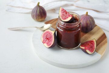 Wall Mural - Board with jar of sweet fig jam on marble background