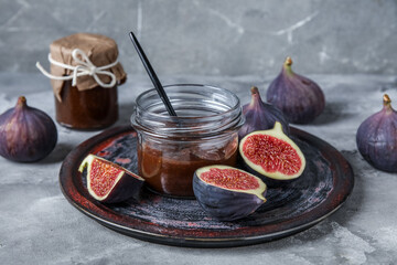 Wall Mural - Plate with jars of sweet fig jam on grey grunge background