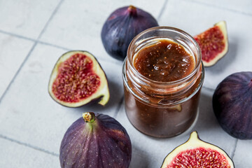 Wall Mural - Jar of sweet fig jam on white tile background