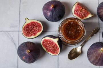 Wall Mural - Jar of sweet fig jam with spoon on white tile background