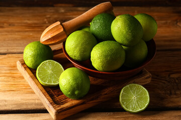 Wall Mural - Bowl and board with fresh ripe limes on wooden background