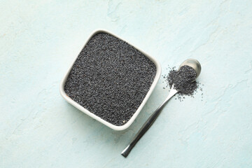 Wall Mural - Bowl and spoon with poppy seeds on light blue background