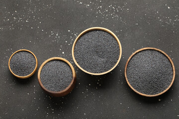 Wall Mural - Wooden bowls with poppy seeds on black background