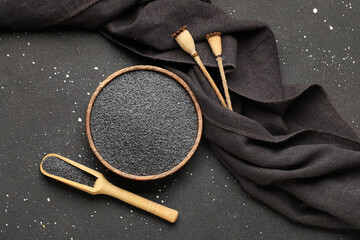 Wall Mural - Wooden bowl and scoop with poppy seeds on black background