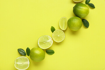 Wall Mural - Fresh ripe limes and leaves on green background