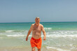 © travelview - attractive senior man at the beautiful sandy beach in swim suit