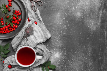 Wall Mural - Cup of hot rose hip tea and plate with berries on grey background