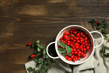 Wall Mural - Colander with fresh rose hip berries and leaves on wooden background