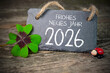 © Stockwerk-Fotodesign - Wooden hang tag and slate with four leaf clover and sparklers with the german words for happy new year - frohes neues jahr 2026 on wooden weathered background