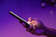 © fadfebrian - A man scrolling on social media apps or searching for information online on his smartphone on blue and purple neon lights background
