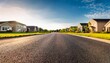 © Karina - asphalt road leading into blurred suburban neighborhood on sunny day low angle view in residential community