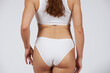 © migfoto - Young beautiful girl in white lingerie stands with his back on a gray background