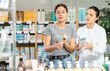 © JackF - Focused young girl choosing cream or skin care product in big pharmacy, young asian woman pharmacist consulting and offering variety of goods to customer