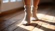 © Sergey - Cozy morning vibes: sunlight on wooden floor with warm socks