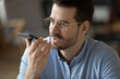 © fizkes - Closeup portrait young businessman speaking on phone using voice app