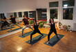 © phoenix021 - Group of three people, two women and young man practicing yoga indoors, doing warrior yoga pose
