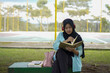 © Fajar - Serene young woman in a hijab and red headphones, deeply engrossed in reading a book while studying outdoors on a tranquil park bench, fostering knowledge and personal growth
