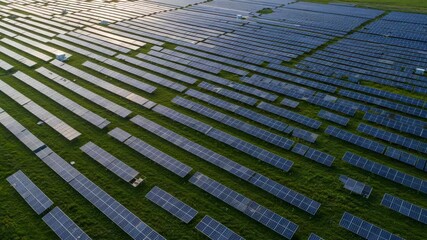 Aerial view of a large solar panel farm in a green field on a sunny day