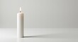 © berkah - A single, tall white candle burns, casting a shadow on a white surface with a grey backdrop