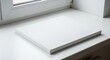 © Siam - A clean and minimalist white canvas rests on a bright windowsill waiting to be transformed by art and imagination showcasing its textured surface and smooth edges