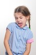© Niko_Dali - Young girl sticking out her tongue, playful expression. Studio shot against a white background.