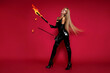 © marcink3333 - Blonde Woman in Shiny Black Latex Suit Holding Fire Baton and Whip Posing on Vibrant Red Background
