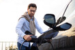 © sofiko14 - A man is plugging in an electric vehicle charger, focusing on sustainable transportation and green energy.